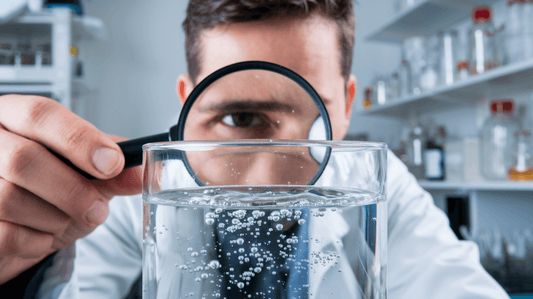 scientist looking at glass of water with magnifying glass